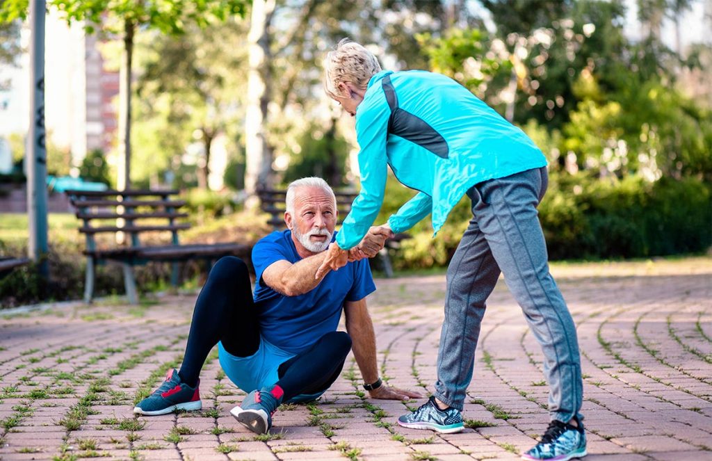 Una mujer ayudando a un hombre a levantarse.