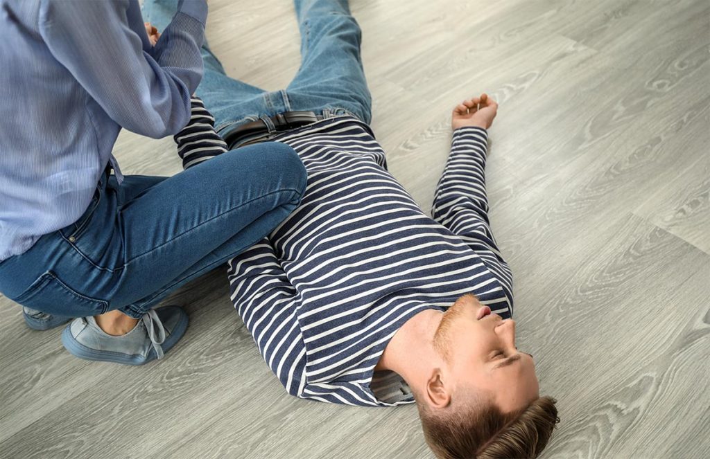 Mujer auxiliando a persona en desmayo.